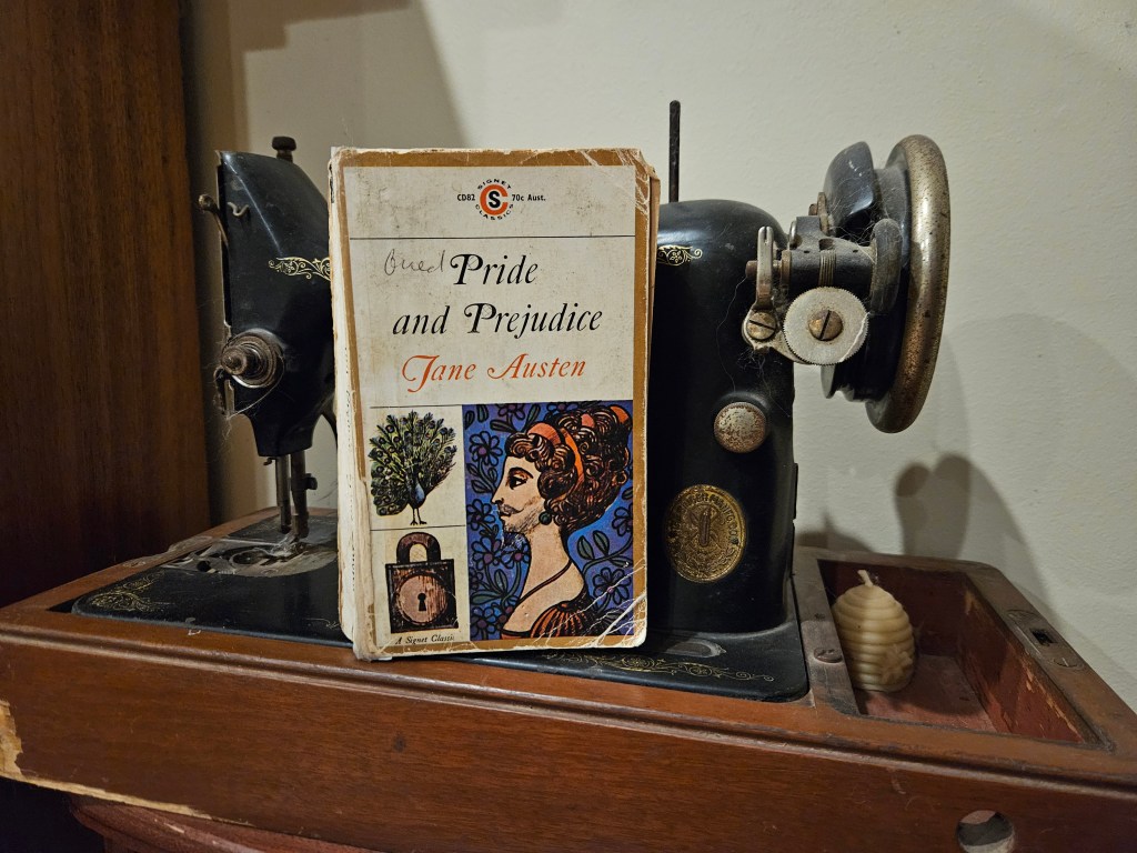 An old copy of pride and prejudice next to an antique Singer sewing machine